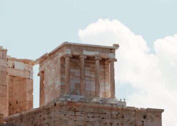 | GoCryptoBet.com Ancient stone temple ruins with tall columns and intricate carvings, set against a partly cloudy sky.