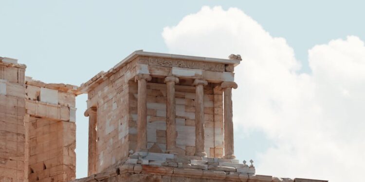 | GoCryptoBet.com Ancient stone temple ruins with tall columns and intricate carvings, set against a partly cloudy sky.